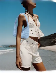 Close-up of light blue hand-woven hobo bag in leather texture shown at beach