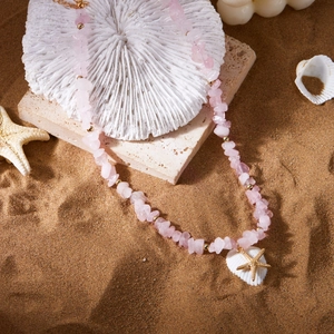 Bohemian pink crystal necklace with gold starfish and shell pendant on beach sand