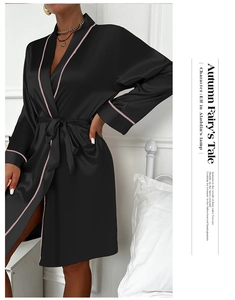 Detail of black satin robe with pink trim showing V-neck design and smooth texture
