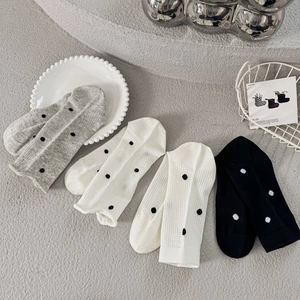 Detailed knit texture of four pairs of polka dot socks in gray, white, and black colors