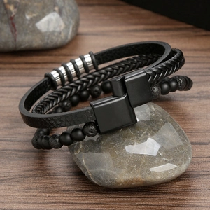 Handmade layered black leather bracelet with onyx beads and lava stones on a polished stone