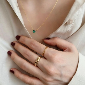 Detail of a 925 silver gold-plated necklace with a green heart pendant and matching rings