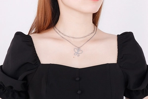 Detail of a silver double-layered butterfly pendant necklace worn by a female model