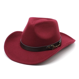 Close-up of deep red felt cowboy hat with brown leather band and gold metal horsebit