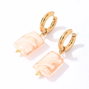 Close-up of gold stainless steel hoop earrings with peach pink marbled resin pendants