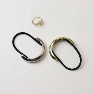 Detail of high-gloss gold and silver alloy hair ties and a crisscross ring on white background