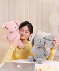 Plush elephant and pig toys shown held by a model in a cozy indoor setting