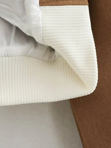 Detailed macro view of the brown fabric texture and white ribbed knit hem of the Y2K jacket