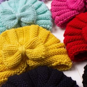 Knitted baby hats with bow detail in multiple vibrant colors on white background