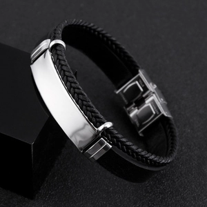 Détail d'un bracelet en cuir tressé noir avec une plaque en acier inoxydable poli