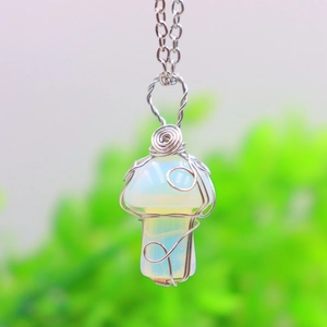 Macro shot of silver wire wrapped mushroom pendant with opal stone on a simple chain