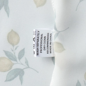 Detailed view of lemon floral print fabric with washing care label and stitching