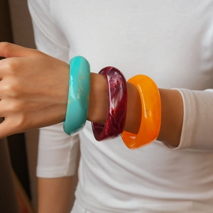 Close-up of vibrant resin bangle set in blue, red, and orange on a female wrist