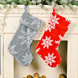 Detail of red and grey plush Christmas stockings with white snowflake patterns on fireplace