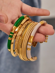 Detail of stacked vintage gold bangles with colorful enamel drip and twisted textures