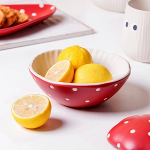 Detail of a red ceramic mushroom bowl with white polka dots and irregular wavy edges