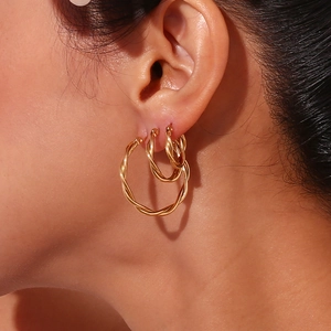 Three sizes of 18K gold plated stainless steel twisted hoop earrings on female model