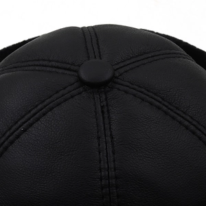 Detailed top view of black PU leather winter cap with double stitching and center button