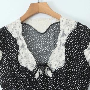 Black polka dot dress with white lace collar and delicate tie detailing on wooden hanger
