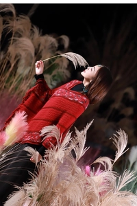 Detail of red ethnic knit poncho featuring diamond patterns and elegant tassel fringe trim