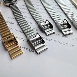 Detail of metal link straps with horizontal texture and folding clasps in gold and silver