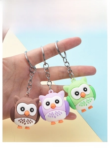 Close-up of cute cartoon owl keychains in brown, purple and green with metal rings
