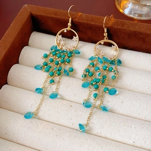 Détail de boucles d'oreilles vintage dorées avec perles turquoise et pompons en cristal