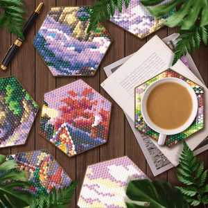 Detail view of six hexagonal diamond painting coasters on a dark wooden desk with green leaves