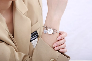 Detailed shot of silver heart charm bracelet engraved with Love mi mama on wrist