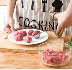 Detail of stainless steel meatball maker scoop being used to shape fresh meatballs