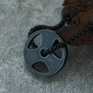 Macro shot of titanium steel dumbbell plate pendant on rugged wood and concrete surface