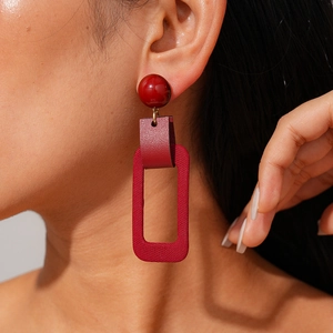 Close-up of geometric wine red leather and resin rectangle drop earrings on model