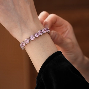Detailed view of pink round-cut zircon tennis bracelet on wrist with silver setting