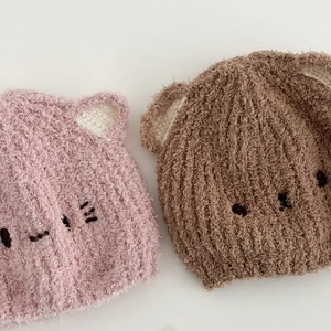 Nahaufnahme von rosafarbenen und braunen Plüsch-Strickmützen mit Tierohren für Babys