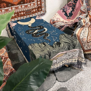 Detail of woven camping blanket with mystic moon, stars, and snake patterns with tassels
