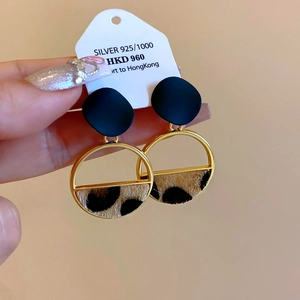 Detail view of gold hoop earrings with leopard print hair and matte black disc accents