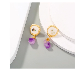 Detailed macro view of vintage gold earrings with crushed shells and purple amethyst pendants