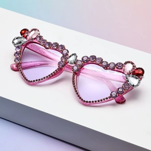 Macro detail of heart-shaped sunglasses with purple rhinestones and glitter finish