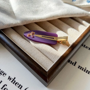 Détail d'une pince à cheveux violette en acétate avec étoiles et strass roses