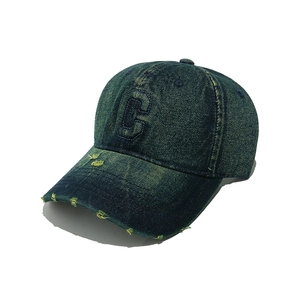 Detailed view of frayed edges and C letter embroidery on washed denim baseball cap