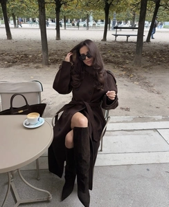 Dettaglio cappotto di lana marrone scuro con stivali scamosciati e borsa coordinata