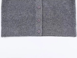 Macro shot of heather grey knit cardigan featuring purple buttons and ribbed hem details