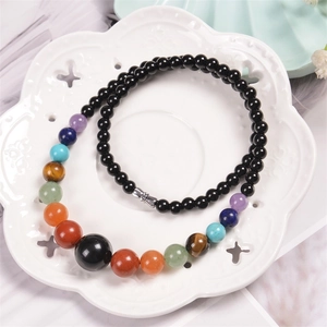 Macro detail of multi-color gemstone beads and black agate beads on ceramic tray