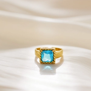 Detail of a gold titanium ring with a square sky blue zircon and twisted rope border