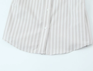 Detailed close-up of grey and white striped poplin shirt hem with white buttons