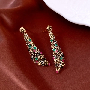 Dettaglio degli orecchini vintage a fiore dorato con strass colorati su seta marrone