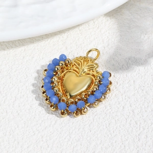 Detail of a gold heart pendant with blue beaded edges and top hanging loop