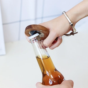 Acacia wood magnetic beer bottle opener in a round design being used on glass bottle