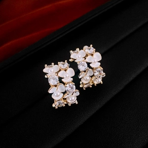 Detail of C-shaped gold earrings with white enamel flowers, pearls and zircons