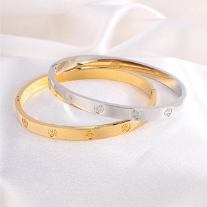 Macro shot of gold and silver stainless steel bangles with star pattern on white silk